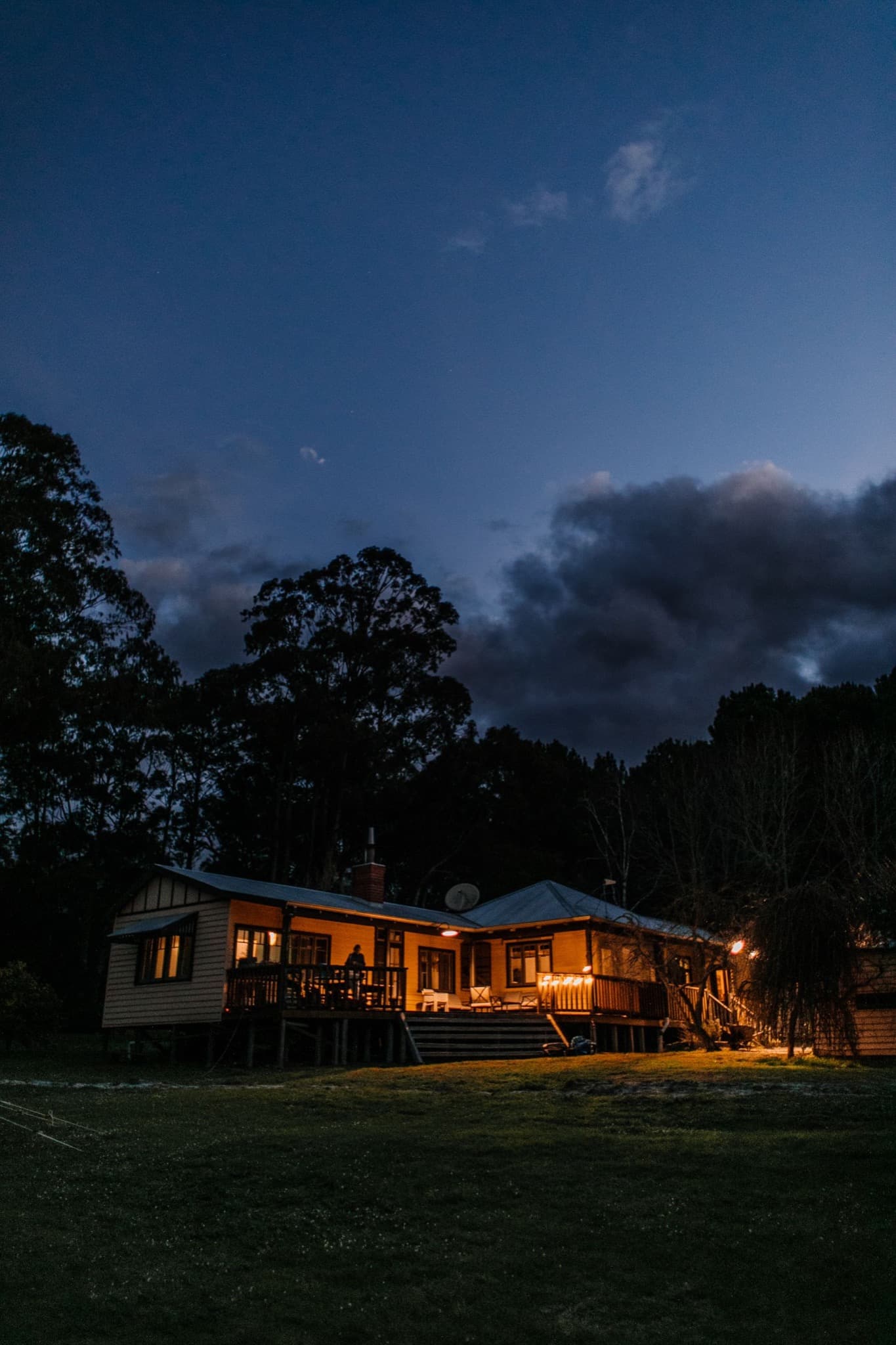 Warmly illuminated home and deck beneath a dark evening sky