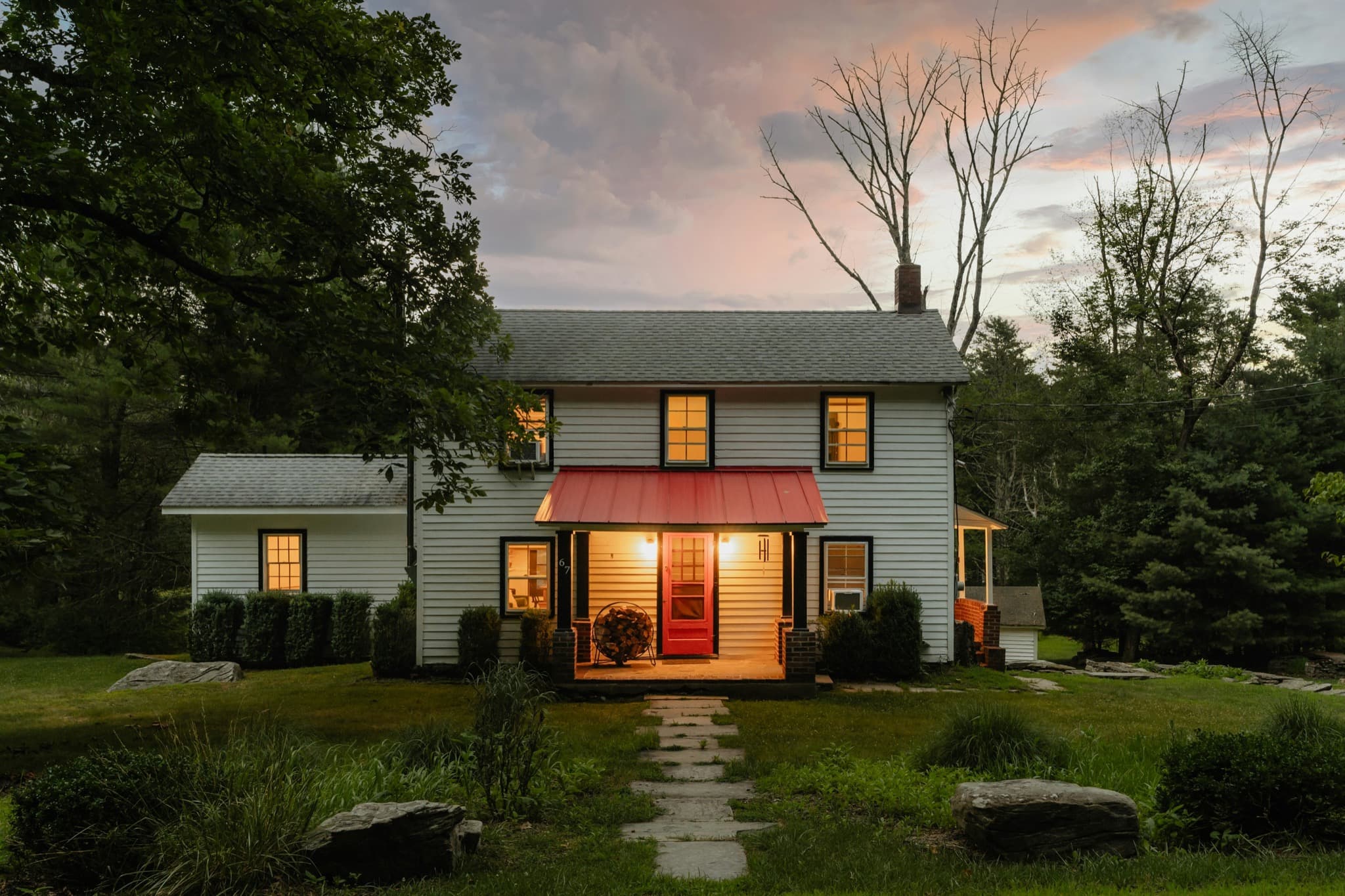 Established white house with illuminated windows at dusk